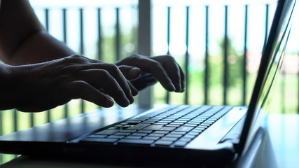 Wall Mural - Silhouette hands of programmer / computer hacker typing coding keys on laptop keyboard, Attack signifying internet theft while using online banking, anonymous business in technology networking concept