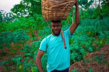 young black happy farmer carrying a basket on his head 