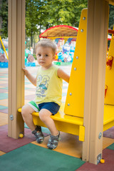 Little baby boy sits at summer playground