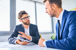© baranq - Two businessmen discussing in office standing by the table