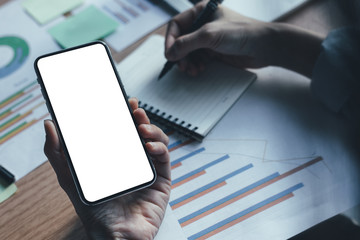 Mockup image blank white screen cell phone.man hand holding texting using mobile on desk at office.background empty space for advertise text.people contact marketing business,technology 