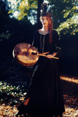 Wall Mural - beautiful shamanic girl playing on shaman frame drum in the nature.