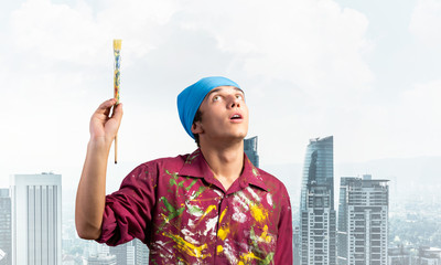 Young painter artist holding paint brush overhead