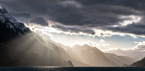 Canvas Print - epic sunrays on a cloudy day over a blue lake in switzerland during winter