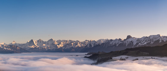 Wall Mural - swiss mountain range in switzerland while the valley is covered in fog during sunset, super warm lig