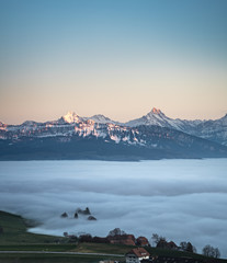 Canvas Print - swiss mountain range in switzerland while the valley is covered in fog during sunset, super warm lig