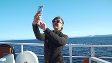 Young Smiling Woman Taking Selfie By Smartphone While Ferry Riding In Slow Motion. Concept Of Holidays, Vacations And Travel