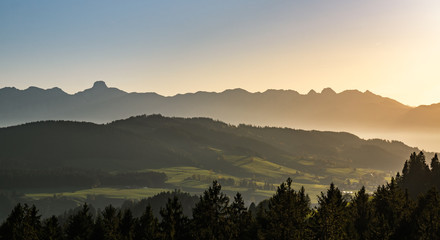Canvas Print - swiss mountain range in switzerland while the valley is covered in fog during sunset, super warm lig