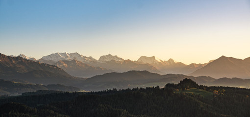 Canvas Print - swiss mountain range in switzerland while the valley is covered in fog during sunset, super warm lig