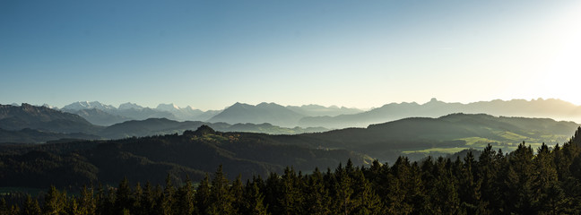 swiss mountain range in switzerland while the valley is covered in fog during sunset, super warm lig