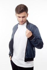 Wall Mural - Young european man in white sweater and black pants, blue bomber jacket posing on white background. Isolated.