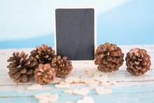 Empty Blackboard For Advertising Text Stand On Vintage Wooden Background Retro Style. Brown Pinecone Or Conifer Cone And Wooden Heart Decoration. Valentine Concept