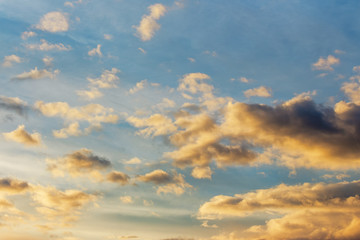 golden clouds on a blue sky at sunset. beautiful nature background. wonderful atmosphere scenery in 