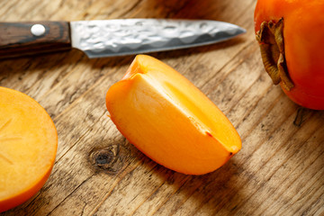 Wall Mural - Raw ripe persimmons fruits slices on wooden board