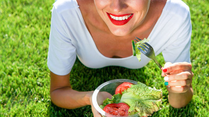 Beautiful caucasian woman eating salad over green natural background