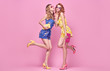 Two Young carefree Woman in stylish playsuit having fun. Beautiful fashionable model girl in trendy summer outfit. Graceful friends with fashion hairstyle, make up on pink. Creative funny concept