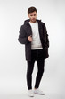 © Alexey - Young european man in white sweater and black pants, black down jacket posing on white background. Isolated.