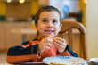 Happy little boy eats pancakes hands. Portrait of small cute little boy child caucasian sitting by the table at home eating pancake
