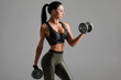 © nikolas_jkd - Fitness woman doing exercise for biceps on gray background. Muscular woman workout with dumbbells