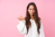 © luismolinero - Young Brazilian girl over isolated pink background unhappy and pointing to the side