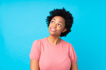 Wall Mural - African american woman over isolated blue background laughing and looking up