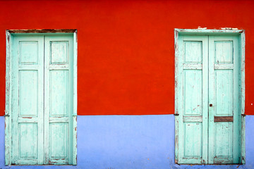 close up on colorful mediterranean style facade with two wooden doors as background