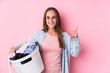 © Asier - Young caucasian woman picking up dirty clothes isolated smiling and raising thumb up