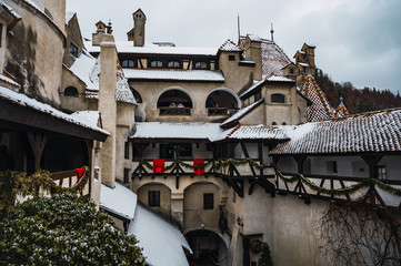 Wall Mural - Bran Castle. Main courtyard of an amazing medieval castle in winter season, snowy roofs and snowy mountains in the background.