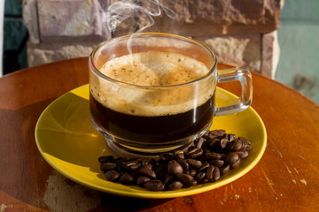 Wall Mural - Clear coffee cups and beans on a wooden table in the morning natural light