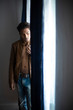© abir - Close up portrait of an young and handsome man with front open leather jacket lightening cigarette while standing in front of a glass door of a balcony. Indian lifestyle.