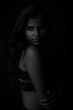 © abir - Monochrome fashion portrait of an Indian brunette Bengali dark skinned woman with black lingerie standing in black studio copy space background. Indian fashion photography and lifestyle.
