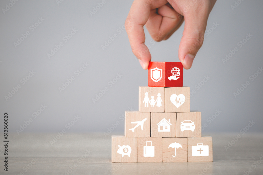 Hand arranging flips wood block stacking with icon insurance: car,  real estate and property, travel, finances, health, family and life, insurance concept.
