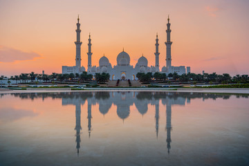 bu Dhabi, UAE, United Arab Emirates: Stunning view of Abu Dhabi Sheikh Zayed Mosque (also known as Grand Mosque) at dusk, reflection in water, illuminated at sunset, golden blue hour