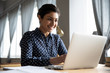 © fizkes - Smiling indian girl student professional typing on laptop at table
