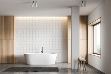 White tile and wood bathroom with tub and column