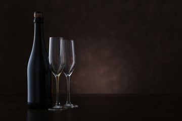 Wall Mural - Bottle of champagne and two glasses on brown background