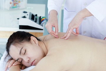 Wall Mural - hand of doctor performing acupuncture therapy . Asian female undergoing acupuncture treatment with a line of fine needles inserted into the her body skin in clinic hospital