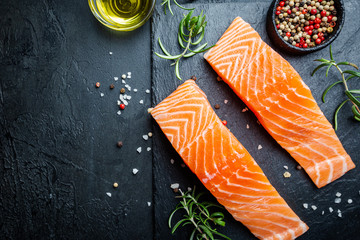 Raw salmon fillet and ingredients for cooking, seasonings and herbs on a dark background . Top view