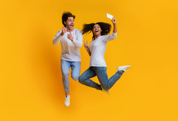 Wall Mural - Joyful interracial couple taking selfie while jumping, having fun together