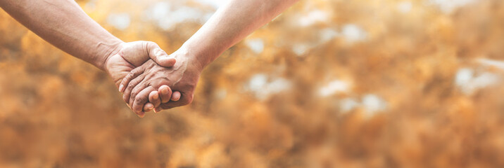 loving senior couple holding hands together over nature background.