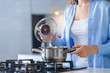 Woman housewife using steel metallic saucepan for preparing dinner in the kitchen at home. Kitchenware for cooking