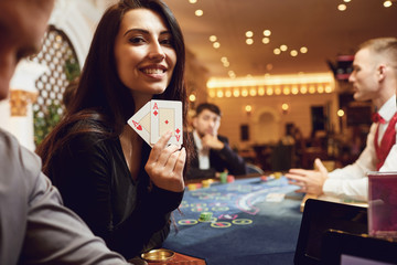 Girl with cards in her hands smiles at winning poker in a casino.