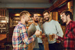 © Studio Romantic - Group of happy friends clinking glasses with beer at a sports bar.