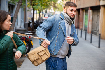 Street thief stealing handbag of woman