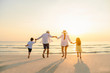 © Garun Studios - Family, travel, beach, relax, lifestyle, holiday concept. Family who enjoy a picnic. Parents are holding hands their children and walking on the beach at sunset in holiday.