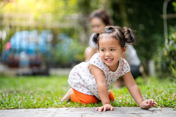 Wall Mural - Happy little girl playing with her mum in park at noon.