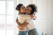 Happy multiethnic girlfriends have fun hugging indoors