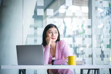 Portrait of a tired and boered young businesswoman sitting at the table with laptop computer in the office.