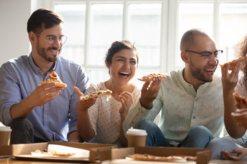 Happy multiethnic millennial friends have fun eating pizza together