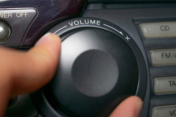 A person turning the volume wheel up or down (the focus is on the word 